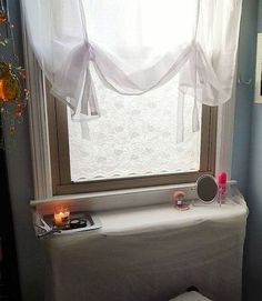 a bathroom with a toilet, window and candles on the windowsill in front of it