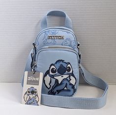 a small blue bag with an image of stitch and stitch on the front, sitting next to a tag