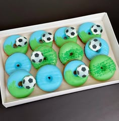 cupcakes decorated with green frosting and soccer balls are in a white box