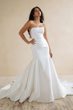 a woman in a white wedding dress posing for the camera with her hands on her hips