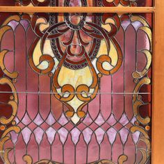 an art nouveau stained glass window with gold and red designs on the outside, in front of a wooden frame