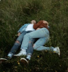 two people are laying in the grass with their arms around each other and one person is hugging