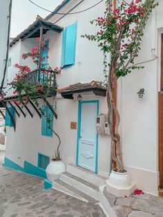 an old house with blue shutters and pink flowers