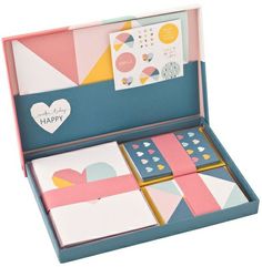 a set of four cards in a blue box with pink, yellow and white designs