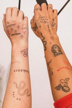 two people with tattoos on their arms hold scissors in front of each other's hands