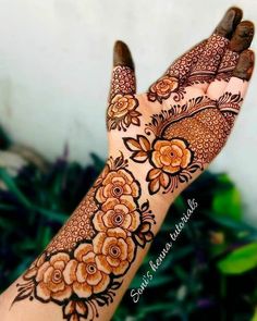 a woman's hand with henna tattoos on it and some flowers in the middle