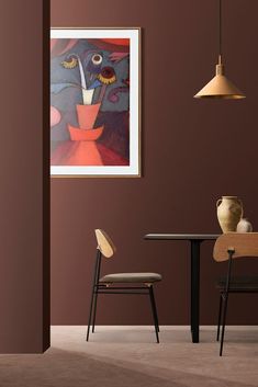 a painting hanging on the wall next to a table with two chairs and a vase