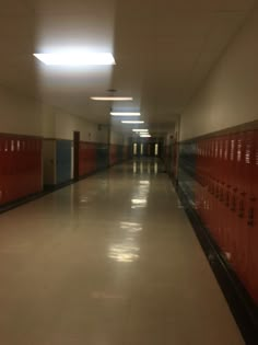 an empty hallway with red lockers on the walls