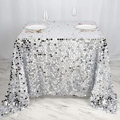 a table covered with silver sequins and two wine glasses on top of it