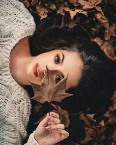 a woman holding a leaf in front of her face