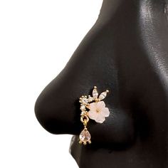 a woman's nose with an earring made out of gold and white flowers