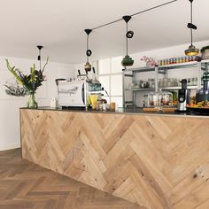 a kitchen with wooden floors and shelves filled with bottles, glasses, and other items