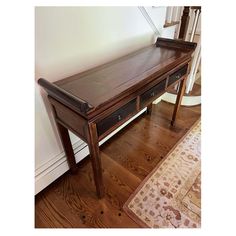 a wooden bench sitting on top of a hard wood floor next to a rug and wall