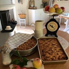 two pans filled with food sitting on top of a table next to an apple pie