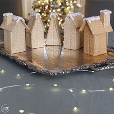 three gingerbread houses on a tray with a christmas tree in the background