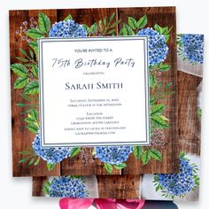 a birthday party with blue flowers and greenery on the front, along with a wooden background