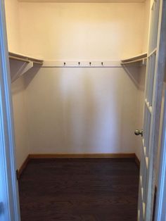 an empty walk in closet with wooden floors and white walls, along with no door