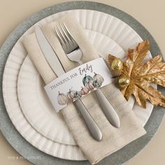 a place setting with silverware, napkins and autumn leaves on the table for thanksgiving dinner