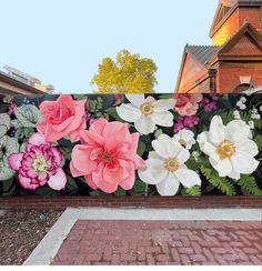 a large floral painting on the side of a fence in front of a brick building