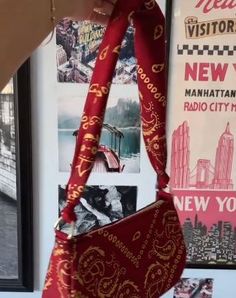 a red purse hanging from the side of a wall with pictures on it and a woman's hand holding it