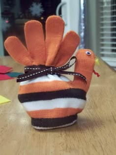 an orange and black knitted bird sitting on top of a wooden table