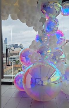 balloons are stacked on top of each other in front of a window with cityscape