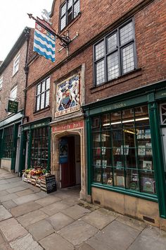 an old brick building with shops on the side and flags flying from it's windows