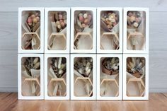 six white boxes with flowers in them sitting on a wooden floor