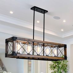 a chandelier hanging over a dining room table with flowers on the table in front of it