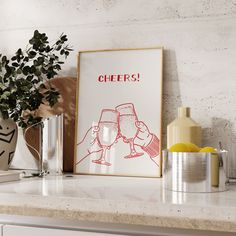 a kitchen counter with a framed poster on top of it that says cheers and two glasses of wine