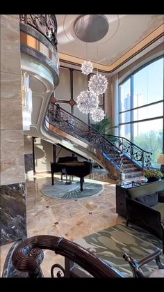 a grand piano sits in the middle of a room with large windows and chandelier