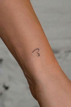 a woman's arm with a small heart tattoo on the left side of her arm