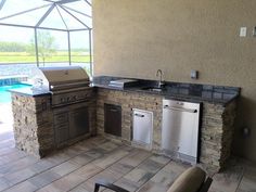 an outdoor kitchen with stainless steel appliances next to a swimming pool and covered patio area