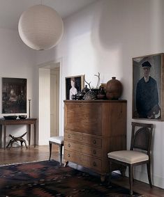 a living room filled with furniture and pictures on the wall next to a rug in front of a dresser