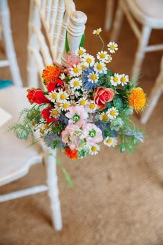 a bouquet of colorful flowers sitting on top of a white chair next to a railing