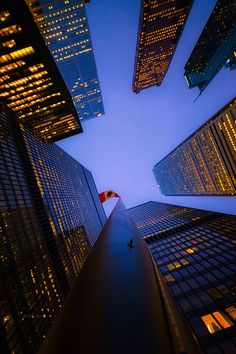 an upward view of skyscrapers at night in new york city, with the canadian flag on top