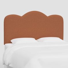 an upholstered headboard for a bed with white sheets and brown linens