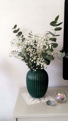 a vase filled with white flowers sitting on top of a table next to a computer