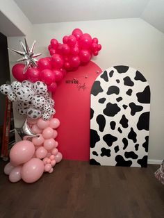 the balloon arch is decorated with cow print and pink, white, and black balloons