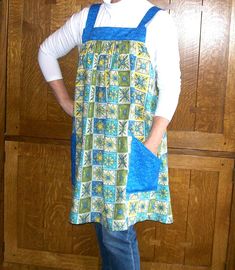 a woman standing in front of a wooden door wearing an apron and smiling at the camera