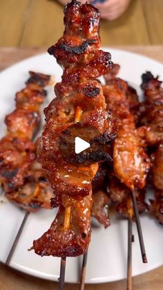 several skewers of meat on a white plate