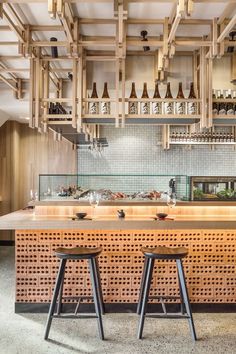 two stools sit in front of a bar with bottles on the shelves above it