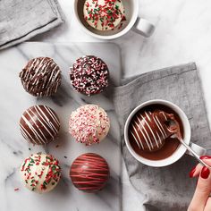 chocolate covered donuts with sprinkles and a cup of coffee on a marble table