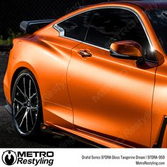 an orange sports car parked in front of a fence