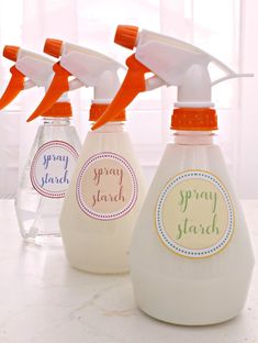 four spray bottles with labels on them sitting on a counter top next to each other