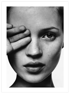 a black and white photo of a woman holding her hand up to her face with the eye