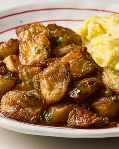 a white plate topped with potatoes and gravy next to mashed potatoes on a table