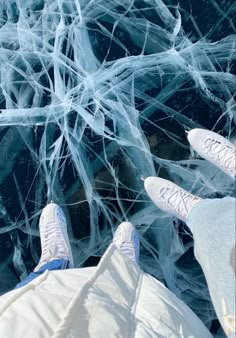 two people standing in front of an ice - covered area with their feet up on the ground