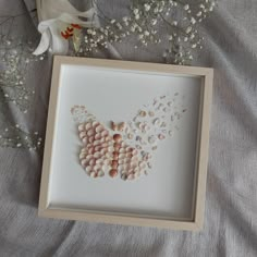 a frame with shells in it next to flowers