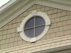 a round window on the side of a building with white trim and brickwork around it